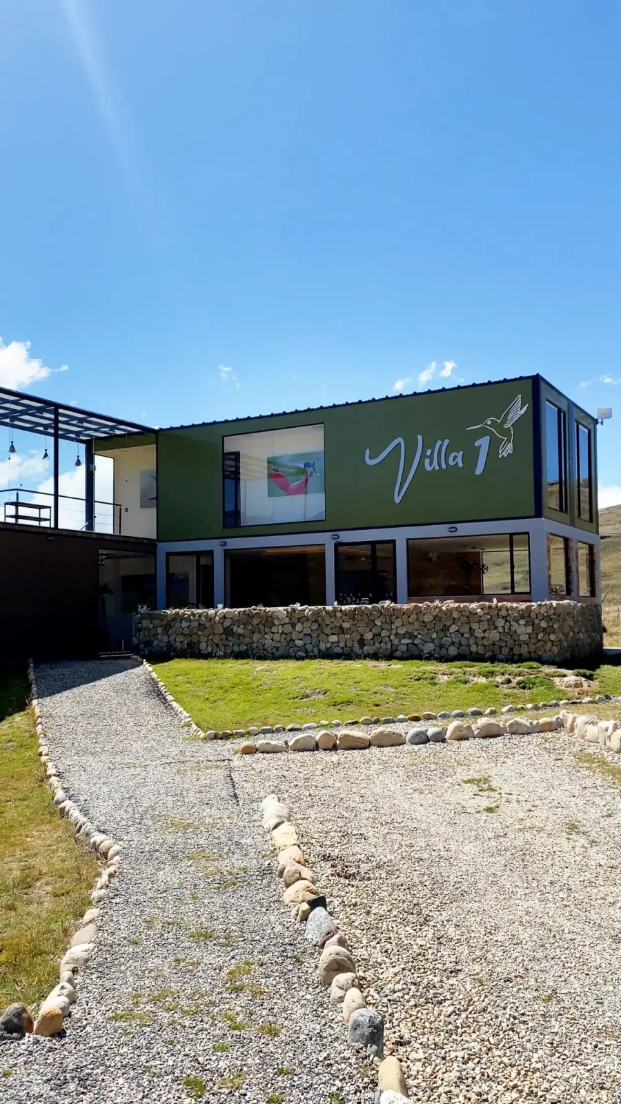 Fachada de la Villa 1 con muro de piedra